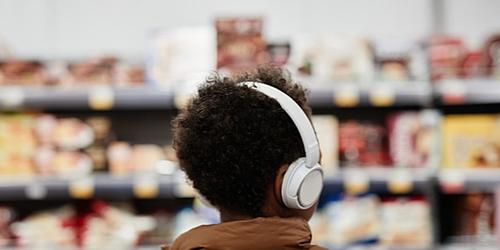 young man shopping in a supermarket wearing headphones